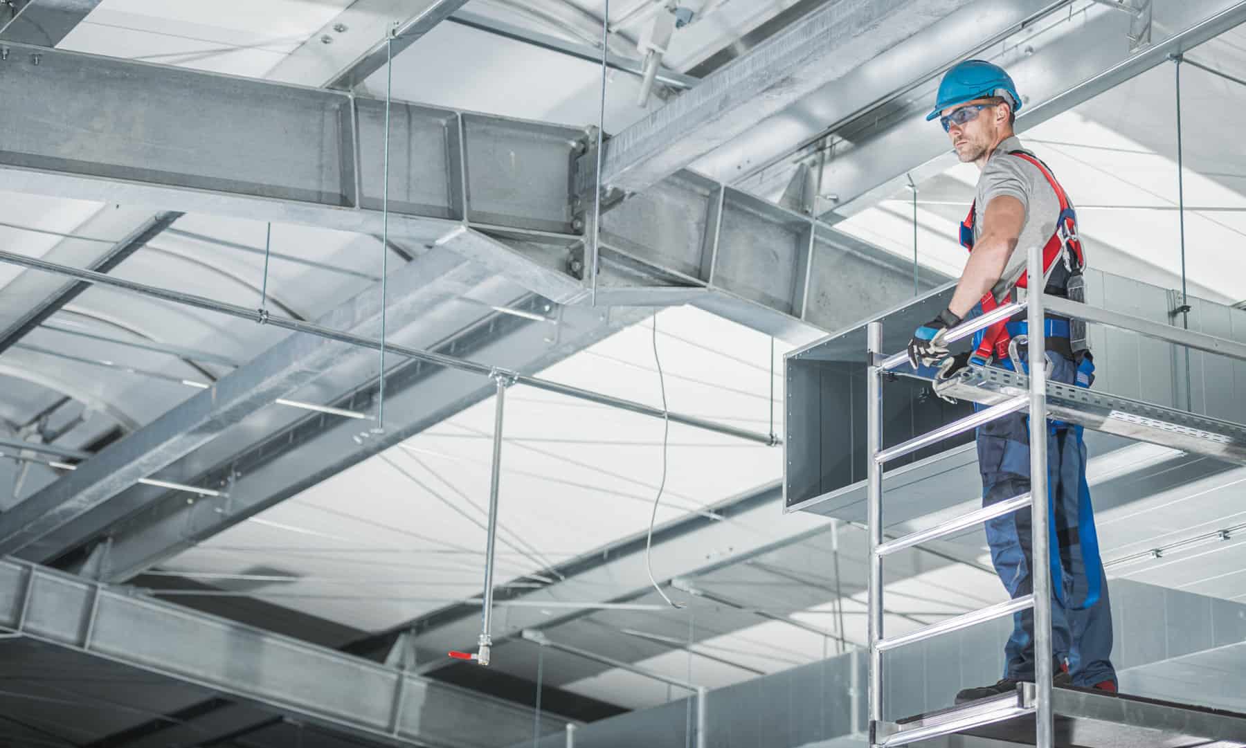 HVAC Technologies Warehouse Air Circulation Installer on Aluminium Scaffolding Preparing to Make Final Air Vents Adjustments.